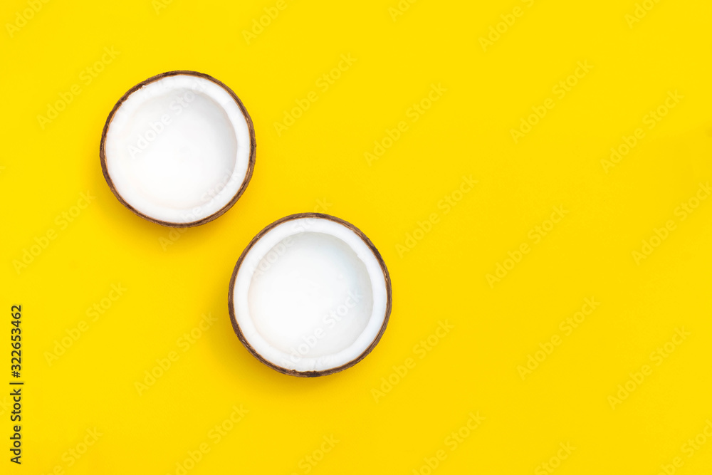 Coconut halves on bright yellow background. Top view with copy space Coconut halves on bright yellow background. Top view with copy space