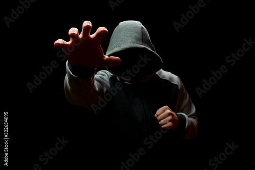Foto A man in a hood reaches out from the darkness. Robbery and Fraud