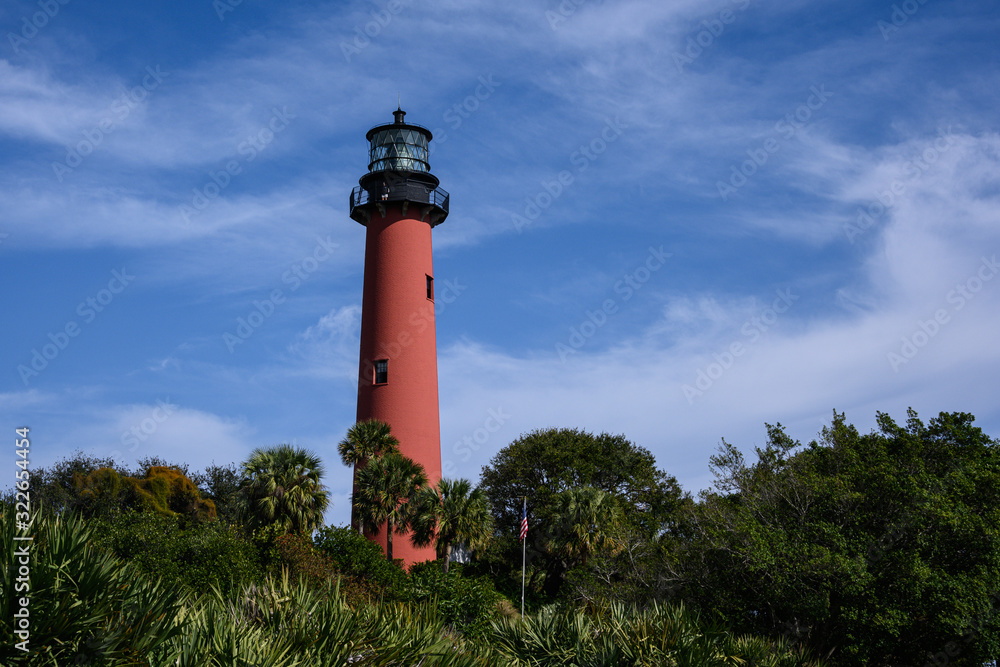 Lighthouse against blue sky and foliage 