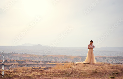 Schilderij op canvas Young bride standing on top of a ridge  waiting for her groom.