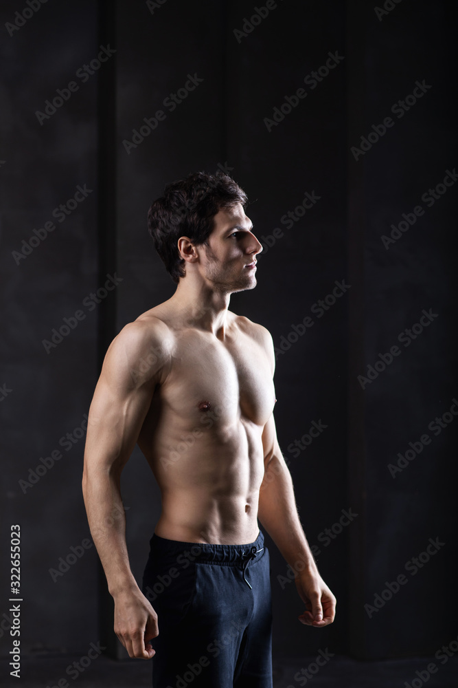 Obraz premium Muscular sports man on dark background. Strong brutal guy