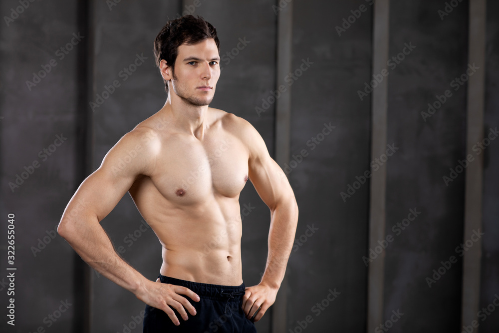 Fototapeta premium Muscular young man in a studio. Portrait of strong brutal guy