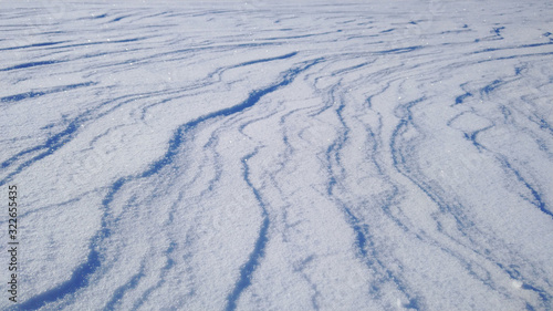 Winter surface of white shiny snow with a shadow from snow drifts