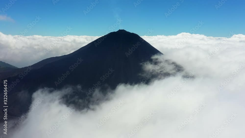 Aerial, drone shot towards the Pacaya mountain, a active volcano, surrounded by clouds, on a sunny day, in Guatemala, Central America Aerial, drone shot towards the Pacaya mountain, a active volcano, surrounded by clouds, on a sunny day, in Guatemala, Central America
