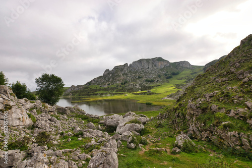 Mountain landscape with rocks, peaks and lakes covered by green grass