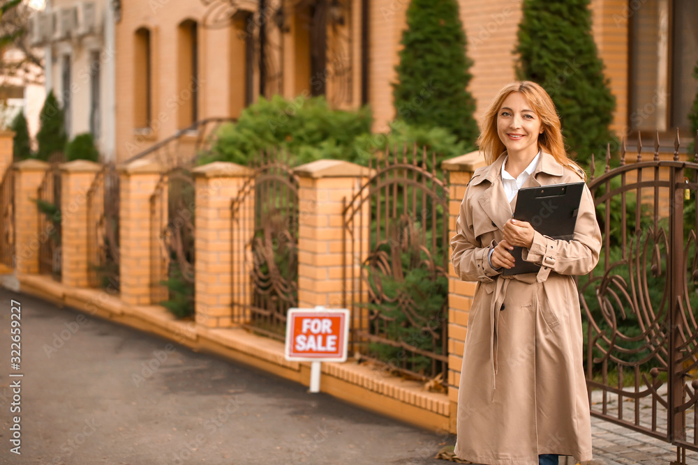 Female real estate agent near house for sale outdoors Female real estate agent near house for sale outdoors