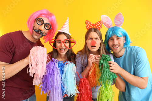 People in funny disguise on color background. April fools' day celebration