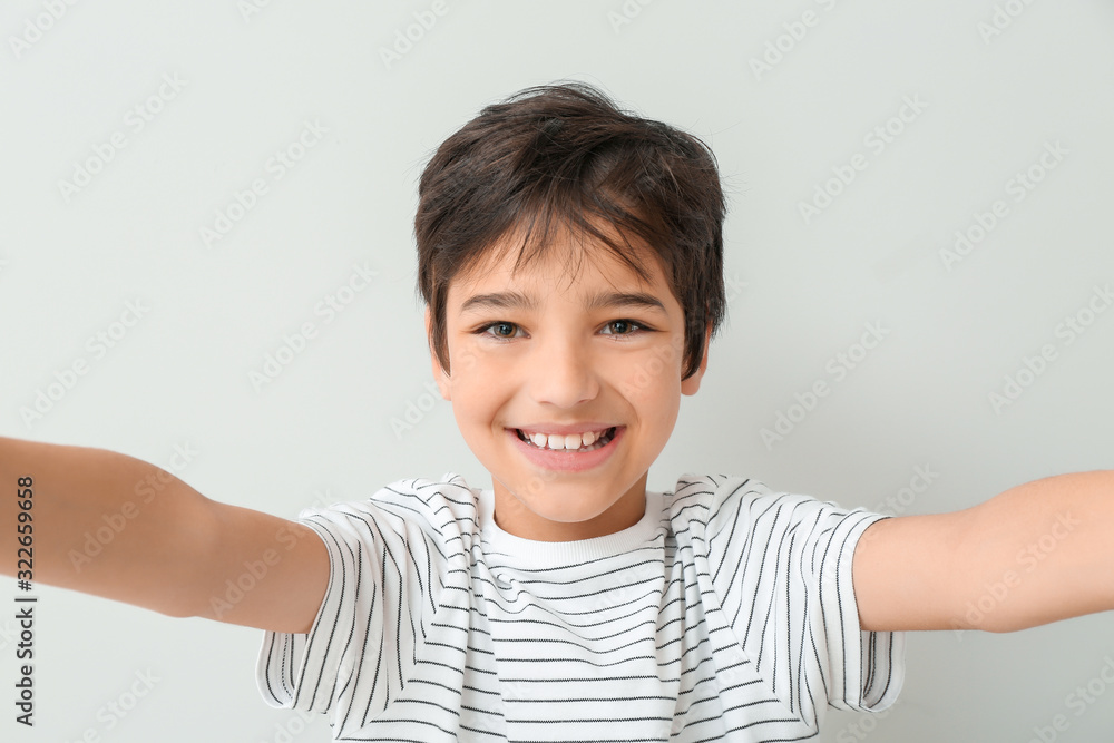 Cute little boy taking selfie on light background Cute little boy taking selfie on light background