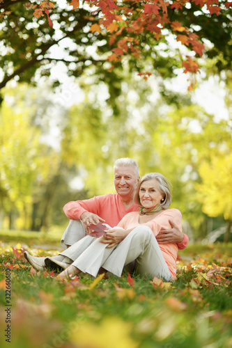 senior couple sitting on autumn leaves in park