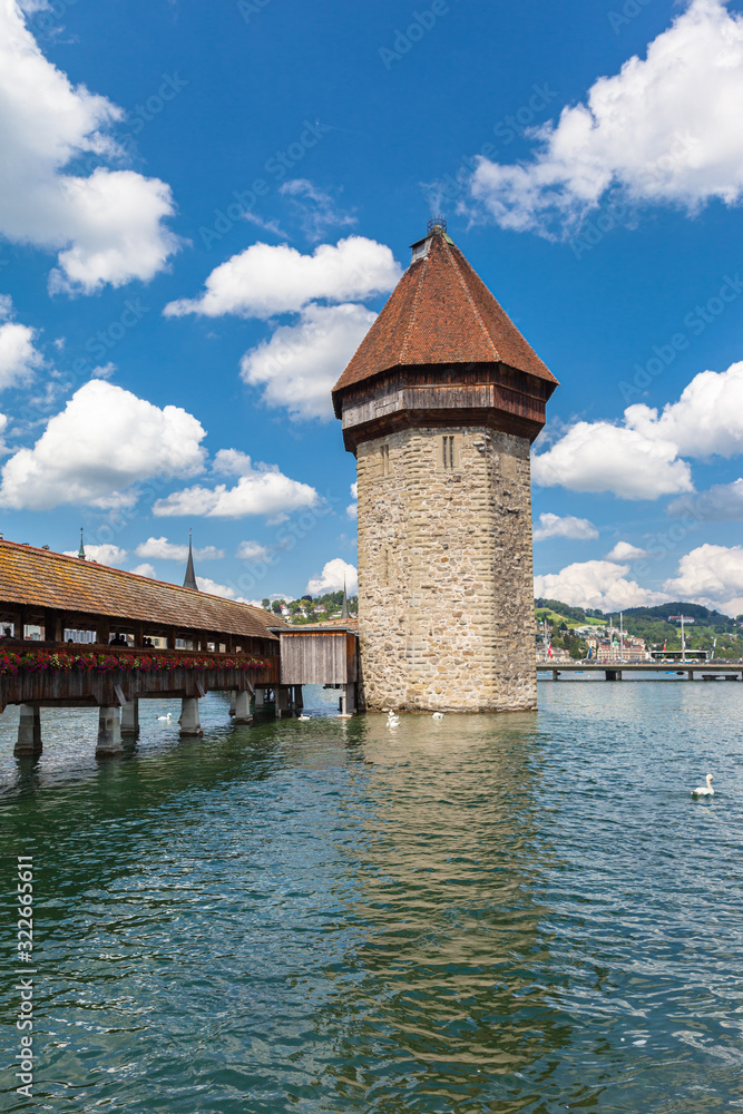 Beautiful closeup view of Chapel Bridge (Kapellbruecke) and Water Tower (Wasserturm) in Lucerne on Reuss river flowing to Lucerne lake, on a sunny summer day with blue sky cloud, Switzerland
