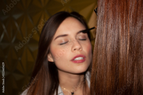 .Straight hair of woman stylist in foreground in background face in effect boque of Mexican Caucasian woman relaxing with eyes closed while makeup photo