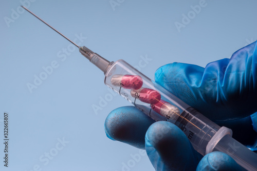 Syringe with pills on a blue background. Pills in a syringe