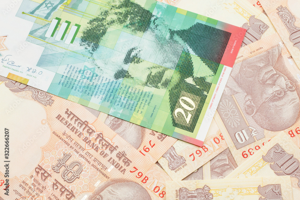 A close up image of a twenty shekel bank note from Israel on a background of Indian ten rupee bank notes in macro A close up image of a twenty shekel bank note from Israel on a background of Indian ten rupee bank notes in macro