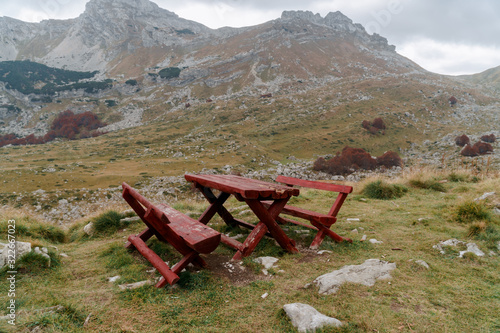Wooden table and benches in the mountains near the cliff. A place for lunch with a gorgeous view