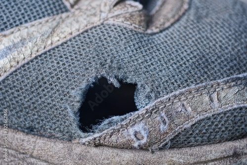 one big black hole on the gray fabric of an old sneaker