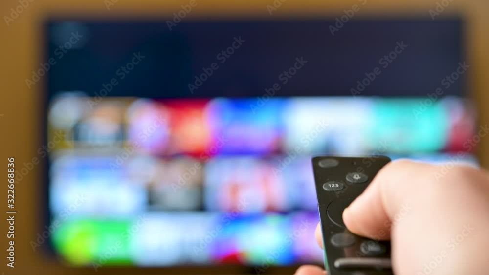 Watch TV. Closeup male hand switches television channels, on the background of the television screen. Interactive tv Watch TV. Closeup male hand switches television channels, on the background of the television screen. Interactive tv
