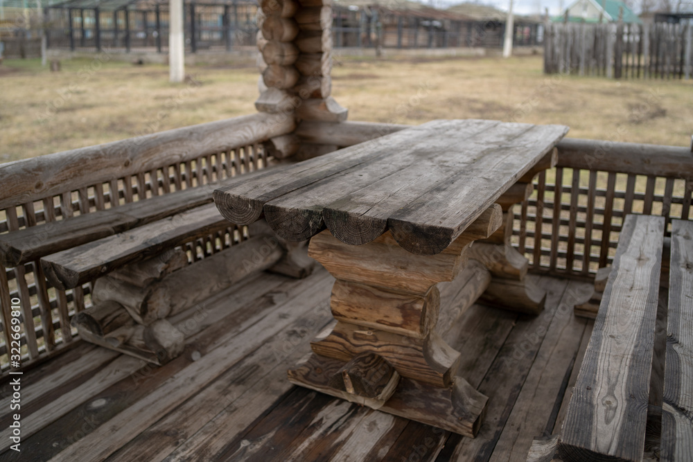 Wooden table with benches in amusement park. Fenced terrace with log table and benches in empty park during gloomy autumnal day Wooden table with benches in amusement park. Fenced terrace with log table and benches in empty park during gloomy autumnal day