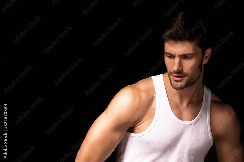 Muscle strong beautiful stripped male model with white shirt in denim gray jeans on black isolated font background Muscle strong beautiful stripped male model with white shirt in denim gray jeans on black isolated font background