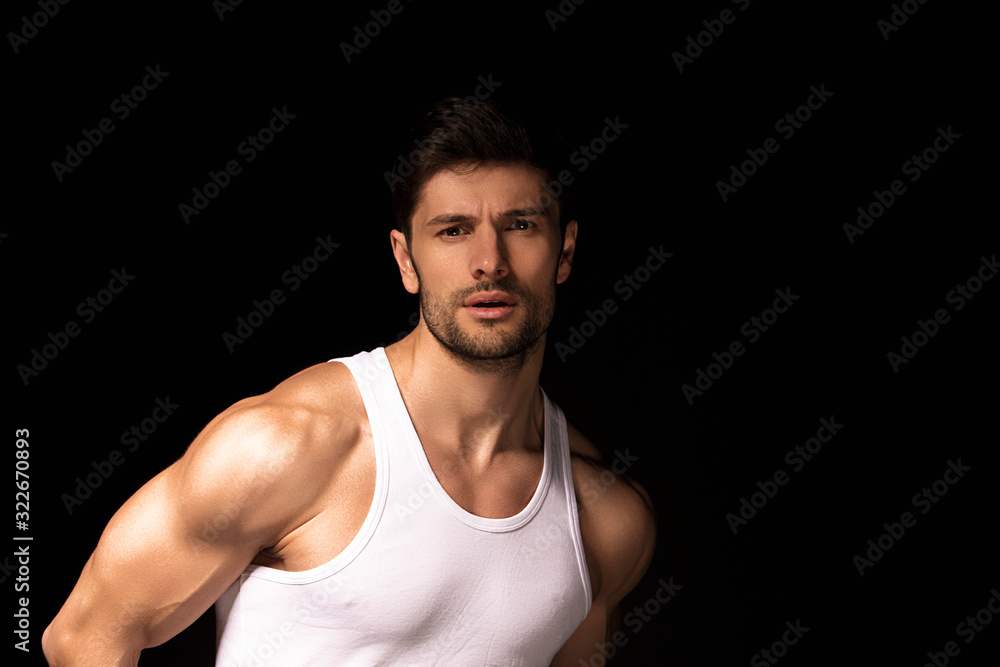 Muscle strong beautiful stripped male model with white shirt in denim gray jeans on black isolated font background Muscle strong beautiful stripped male model with white shirt in denim gray jeans on black isolated font background