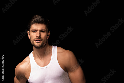 Muscle strong beautiful stripped male model with white shirt in denim gray jeans on black isolated font background