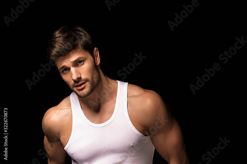Muscle strong beautiful stripped male model with white shirt in denim gray jeans on black isolated font background