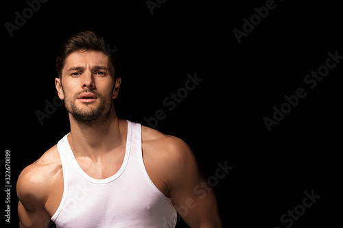 Muscle strong beautiful stripped male model with white shirt in denim gray jeans on black isolated font background