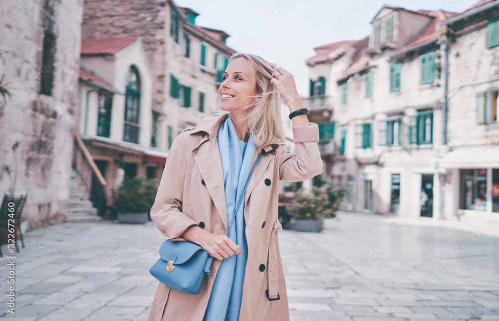 Traveling by croatia. happy young woman in coat walking by Split Old Town.