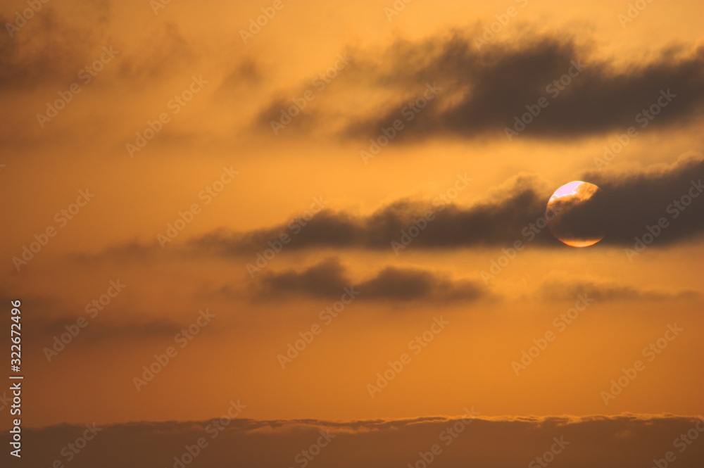 The sun rising over a sea of clouds leaves the sky in orange colors The sun rising over a sea of clouds leaves the sky in orange colors