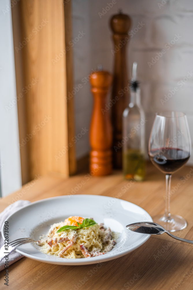 Spaghetti carbonara with pancetta, eggs and cheese in white bowl on the wooden table Spaghetti carbonara with pancetta, eggs and cheese in white bowl on the wooden table