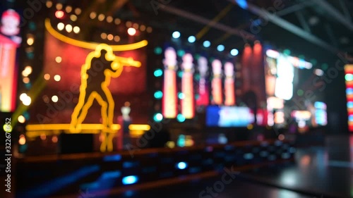 Blurred background of an esports event. Main stage, lights and flashes, illumination, big screens with game moments. Players compete on a stage.