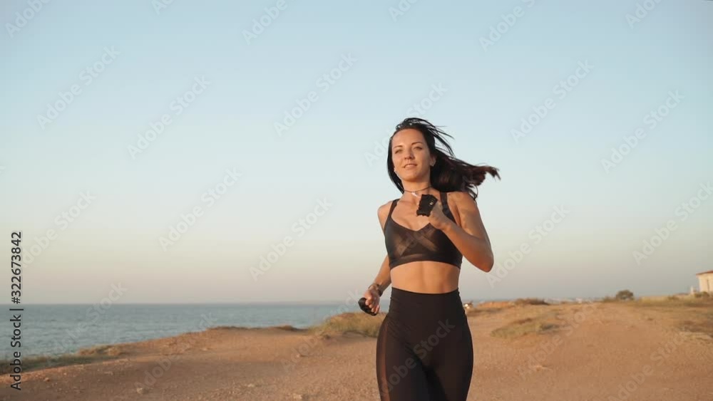 Young adult sporty girl running near sea, training outdoors Young adult sporty girl running near sea, training outdoors