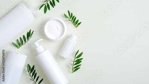 Natural organic SPA cosmetic products set with green leaves. Top view herbal skincare beauty products on green background. Banner mockup for eco shop or beauty salon. Flat lay minimalist style
