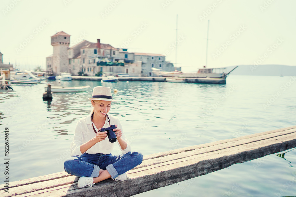 Tourism concept. Young traveling woman enjoying the view of Kastel Gomilica Castle sitting near the sea on Croatian coast.