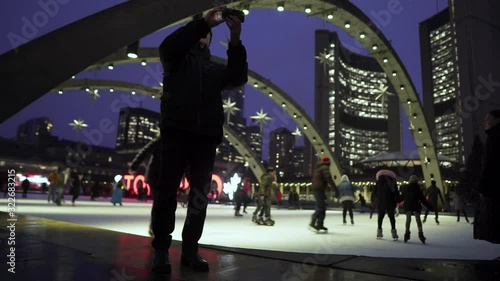 Man taking selfie in front of ice-skating rink at night. photo