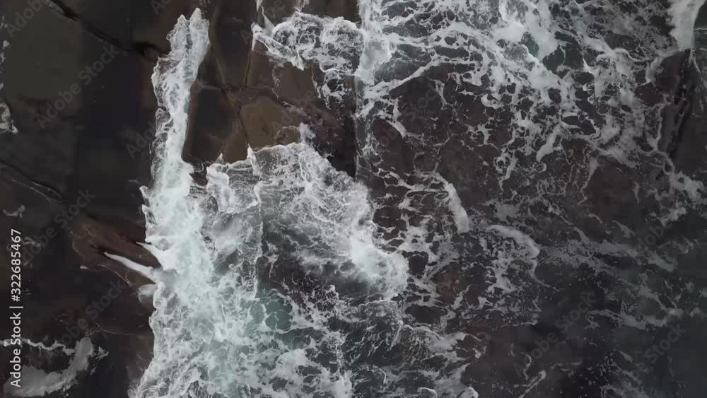 Top down drone view of waves from the sea crashing on rocky cliffs in Senja, Norway. Top down drone view of waves from the sea crashing on rocky cliffs in Senja, Norway.