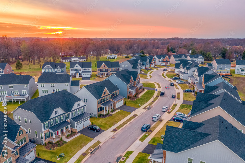 Aerial sunset panorama of luxury real estate development single family house neighborhood curving street with dramatic sky in Maryland USA