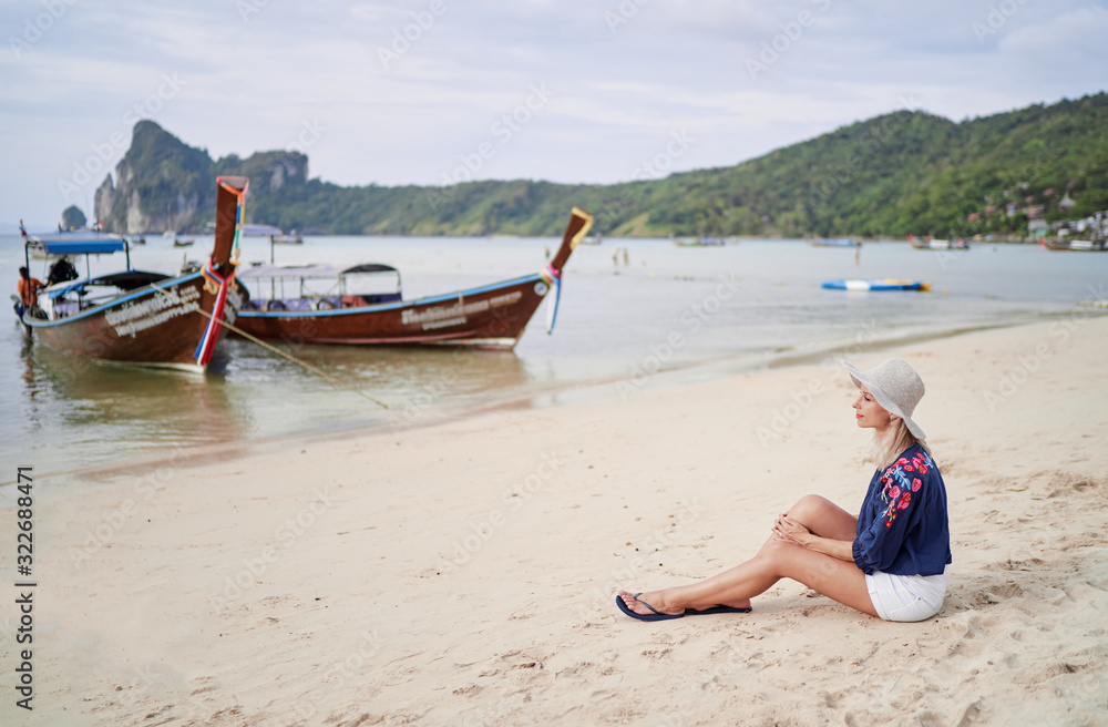 Tropical vacation. Happy young woman with hat sitting on beach enjoying beautiful view in Thailand. Tropical vacation. Happy young woman with hat sitting on beach enjoying beautiful view in Thailand.