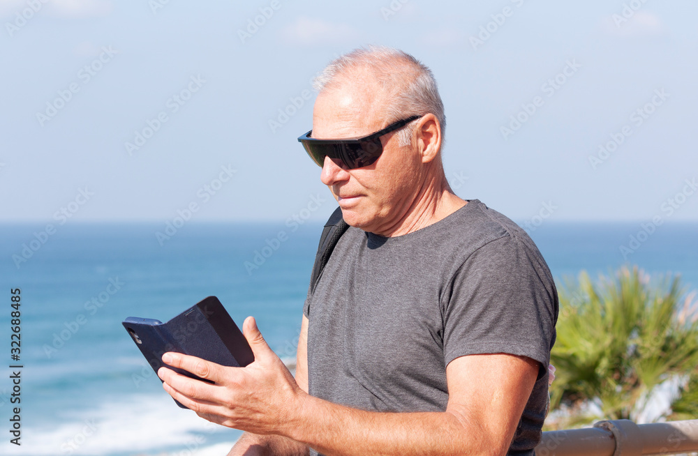a tourist reading a message on his smartphone against the sea