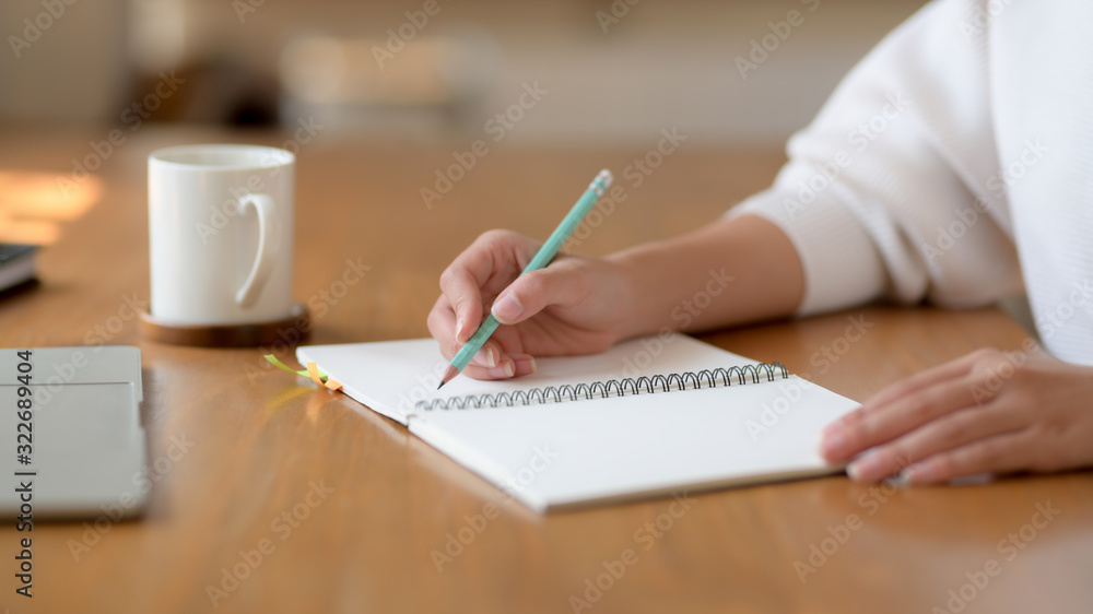 Cropped shot of girl working on her project while writing on notebook Cropped shot of girl working on her project while writing on notebook