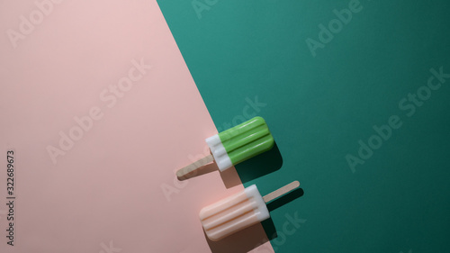 Overhead shot of green tea and strawberry flavour popsicles and copy space on flat lay green and pink background