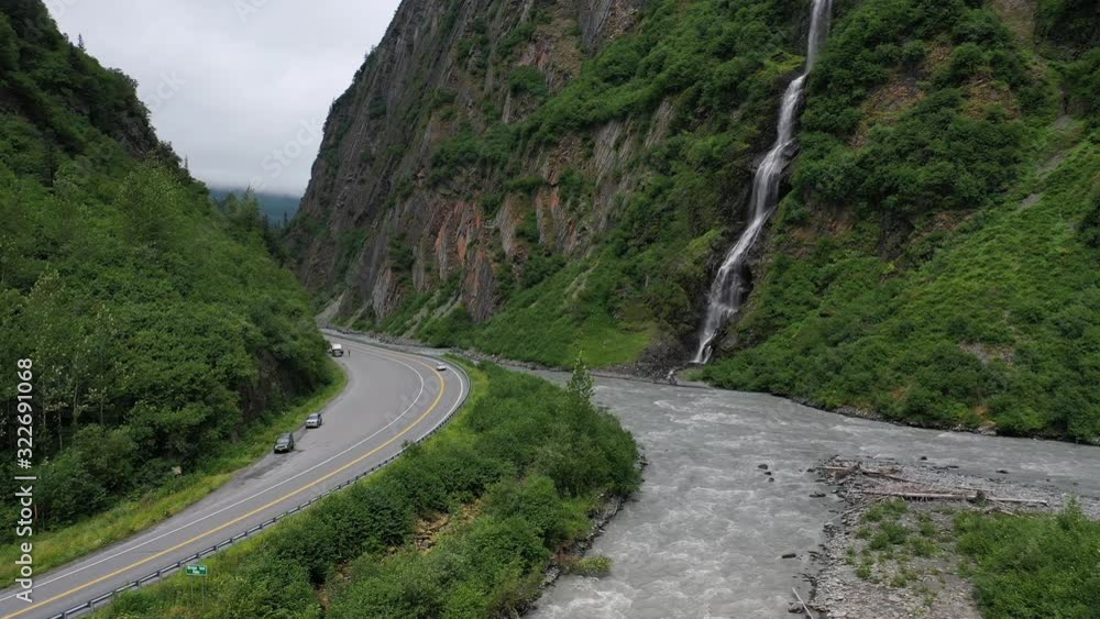 Drone hovering in Keystone Canyon with waterfalls dropping into the river, with tourists looking on from parked cars. Drone hovering in Keystone Canyon with waterfalls dropping into the river, with tourists looking on from parked cars.