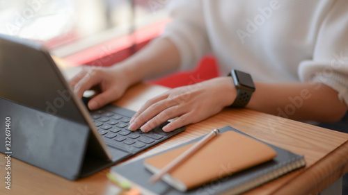 Cropped shot of female freelancer typing on digital tablet