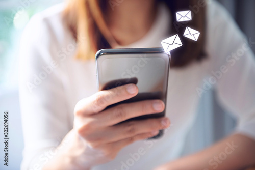 Email concept, Closeup Woman hand using mobile smartphone with email icon. photo