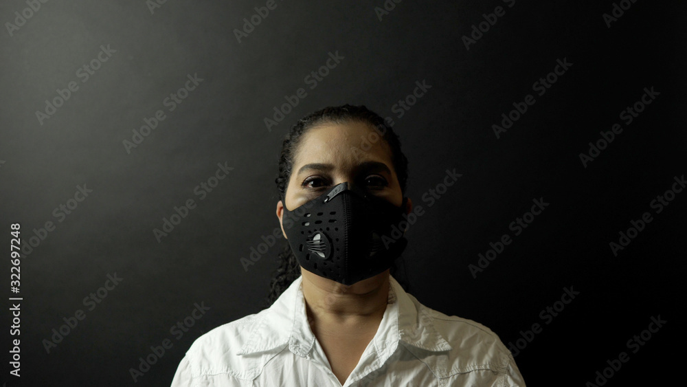 Close up of self protected African American female face in white shirt and urban protective black mask. Prevention and protection infection by deadly coronavirus 2019-nCoV, pandemic in China concept. Close up of self protected African American female face in white shirt and urban protective black mask. Prevention and protection infection by deadly coronavirus 2019-nCoV, pandemic in China concept.