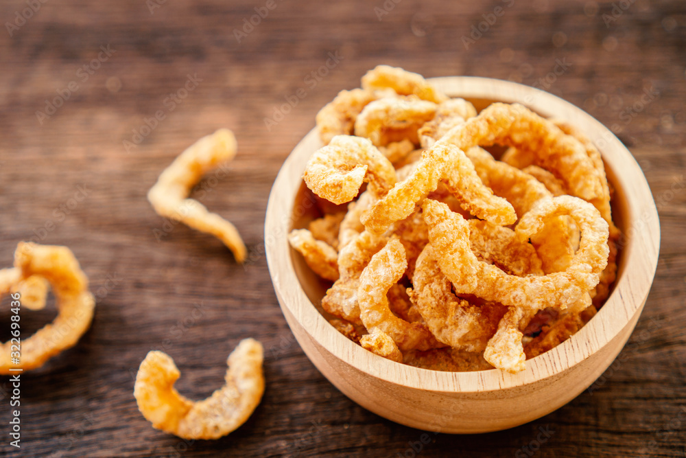 pork snack, rind, scratching or pork crackling in bowl on wooden table pork snack, rind, scratching or pork crackling in bowl on wooden table