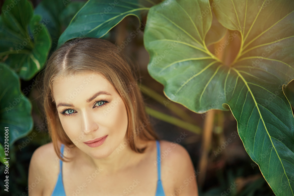 Close up outdoor portrait of young beautiful woman with long hair against green tropical leaves. Close up outdoor portrait of young beautiful woman with long hair against green tropical leaves.