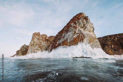 Russia. Lake Baikal. March. Rock 3 brothers. Big beautiful rock in orange shades covered with ice. Around is also a lake covered with ice.