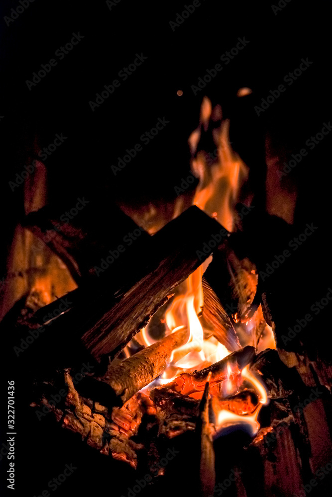 three burning billets in hot stove.Fire flame burning coal and wood in fireplace.Hot coals in the fire.Flames of a campfire in the night.Toned image three burning billets in hot stove.Fire flame burning coal and wood in fireplace.Hot coals in the fire.Flames of a campfire in the night.Toned image