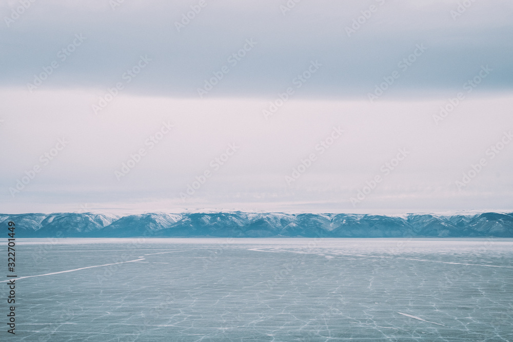 Baikal. Island Olkhon. Lake Baikal covered by people. Around the mountains are covered with snow. March. Photo in blue shades