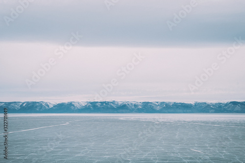 Baikal. Island Olkhon. Lake Baikal covered by people. Around the mountains are covered with snow. March. Photo in blue shades